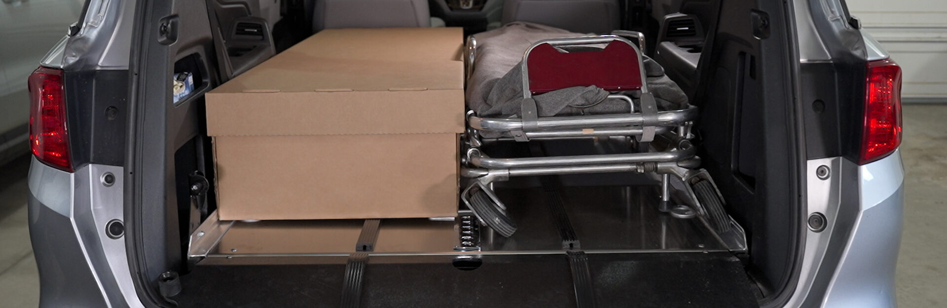 A cremation container and cot side by side on a SS150 Single Deck in the rear of a van