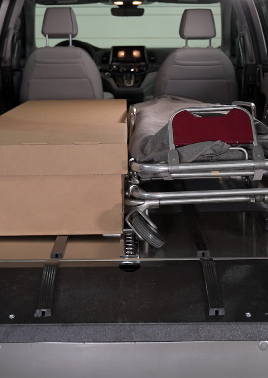 A cremation container and cot side by side on a SS150 Single Deck in the rear of a van