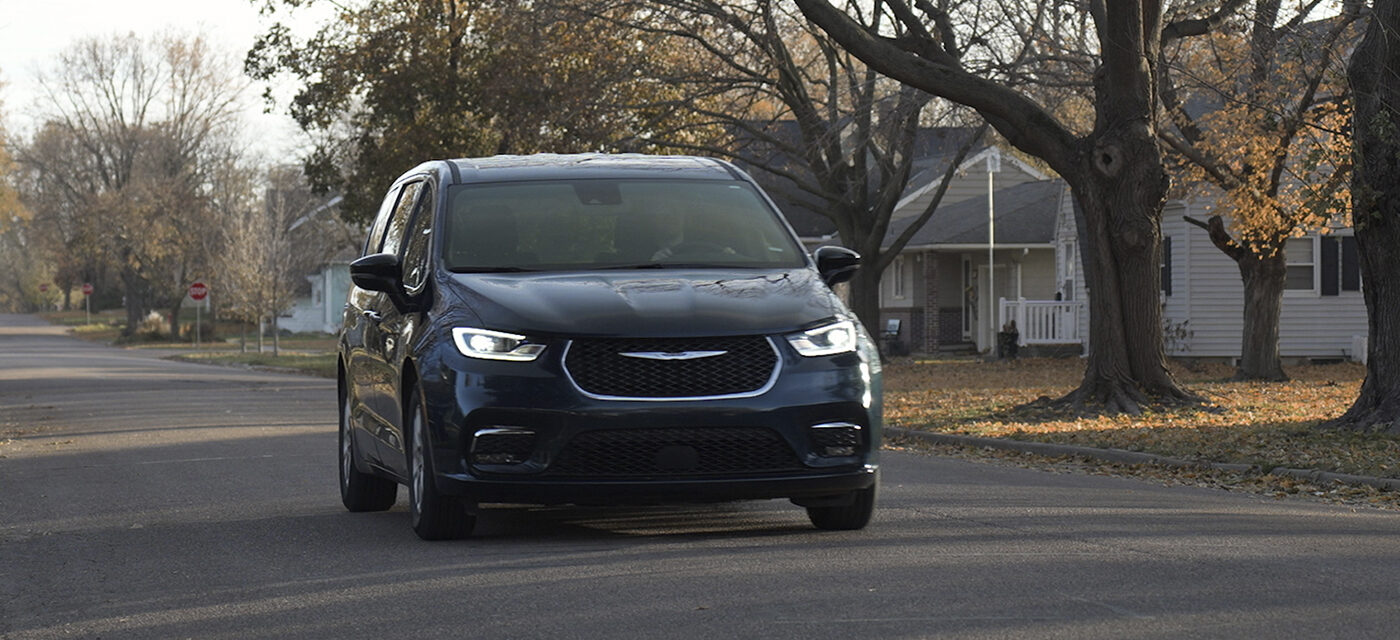 A Chrysler Pacifica driving down a neighborhood road