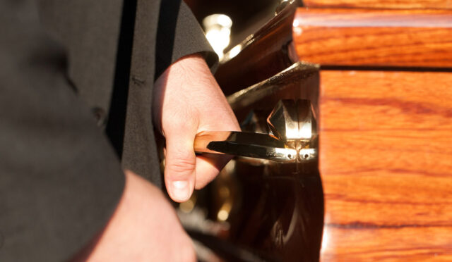 A man holding a handle on a casket